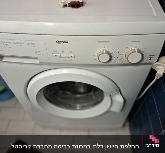 מכונת כביסה עם כפתורי שליטה וחלק חשמלי על המכסה